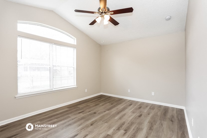 the spacious living room with hardwood floors and a ceiling fan