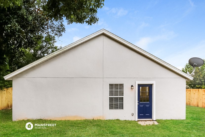 the outside of a white house with a blue door