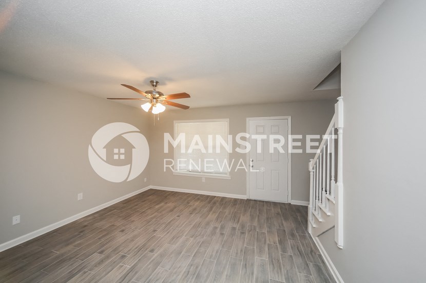 a living room with a staircase and a ceiling fan