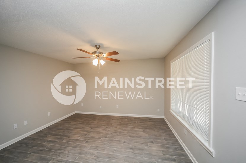 a spacious living room with a ceiling fan and a large window