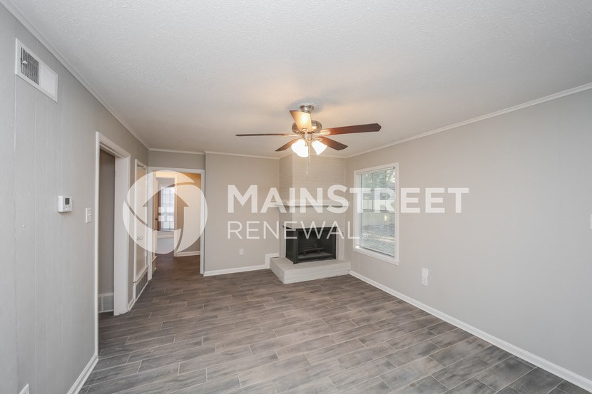 a living room with a ceiling fan and a door to a hallway