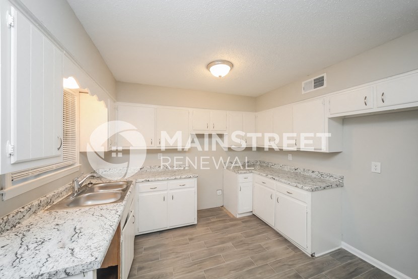 a kitchen with white cabinets and marble counter tops and a sink