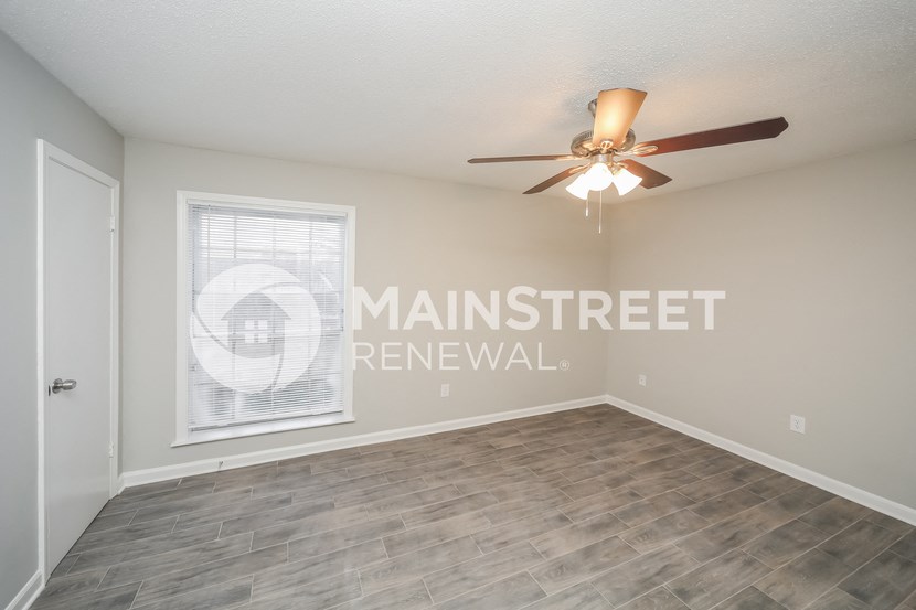 an empty living room with a ceiling fan and a window