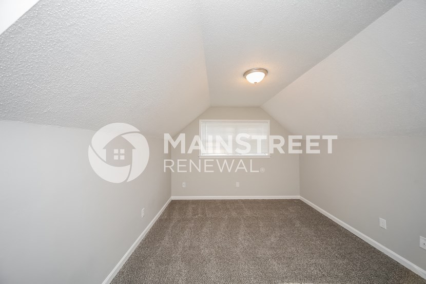 a room with carpet and white walls and a window