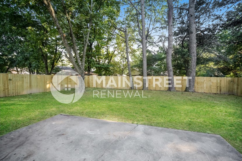 a backyard with grass and trees and a fence