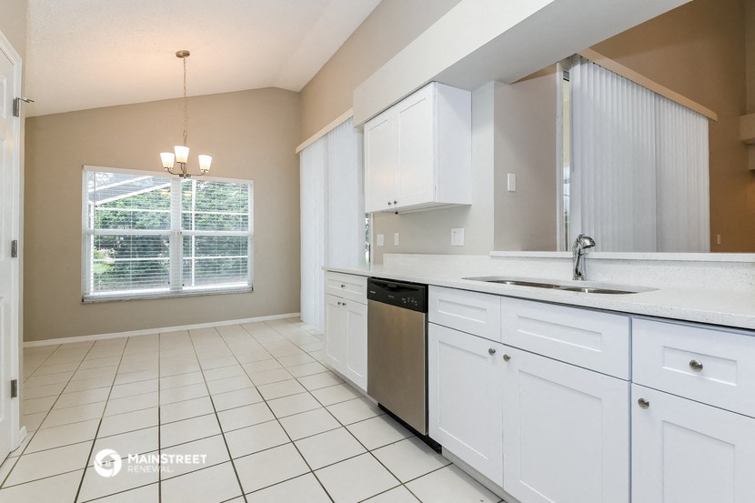 an empty kitchen with white cabinets and a window