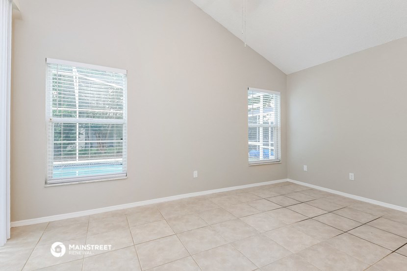 an empty living room with two windows and a tiled floor