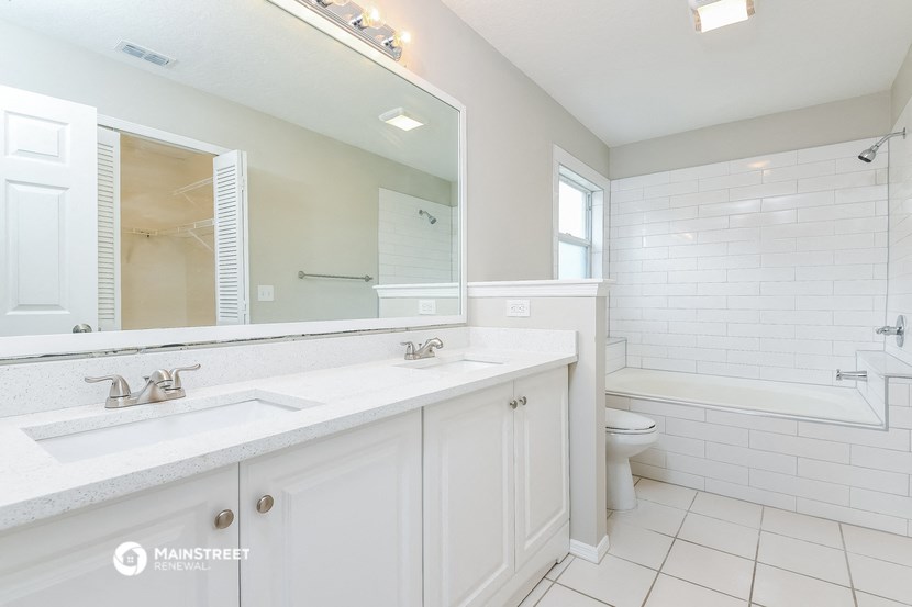 a bathroom with a large mirror and a sink and a toilet