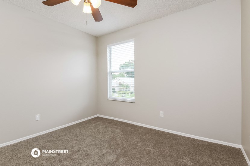 an empty room with a window and a ceiling fan