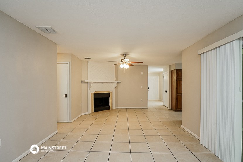 a living room with a fireplace and a ceiling fan