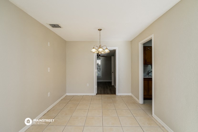 an empty hallway with tile flooring and a chandelier