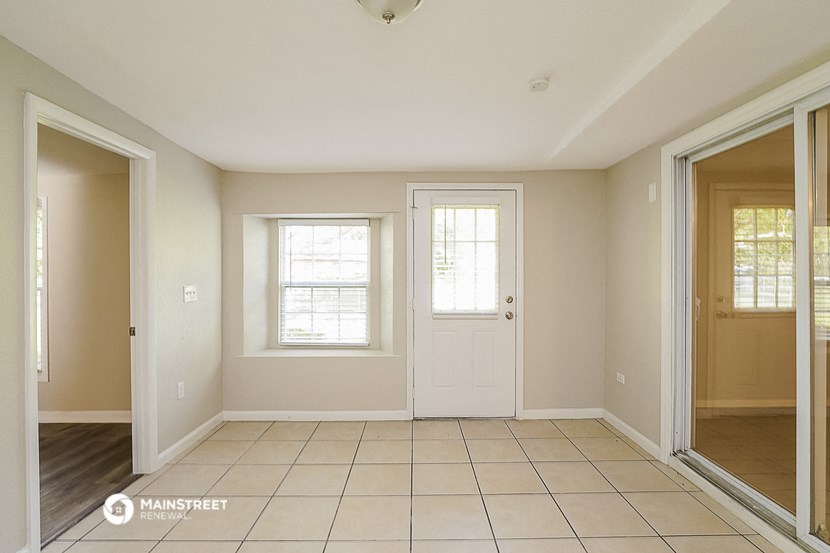 an empty living room with a white door and windows