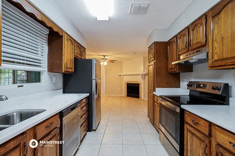 a kitchen with wooden cabinets and white counter tops and a black refrigerator