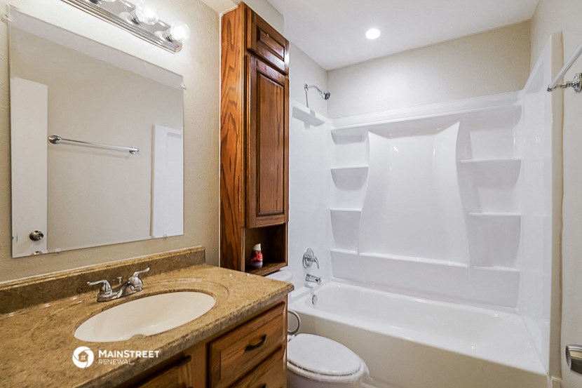 a bathroom with a tub sink and toilet and a mirror