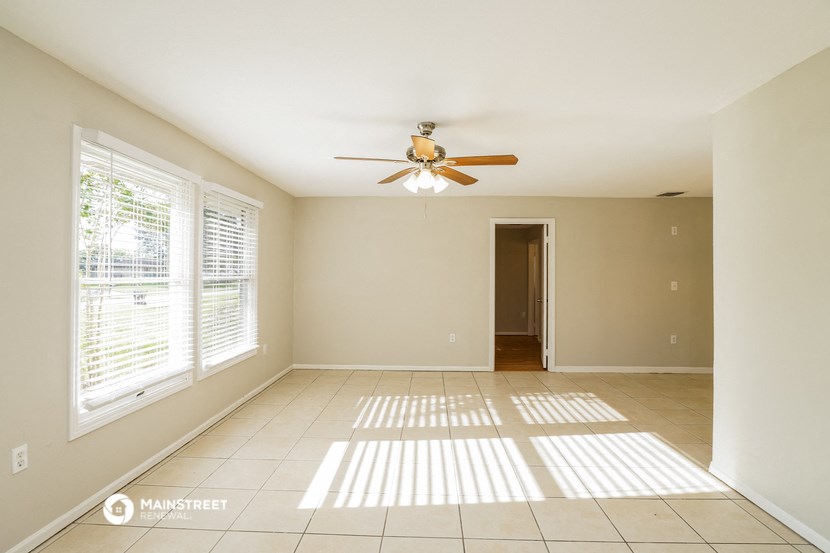 an empty living room with a ceiling fan