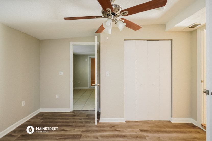 an empty living room with a ceiling fan and a closet