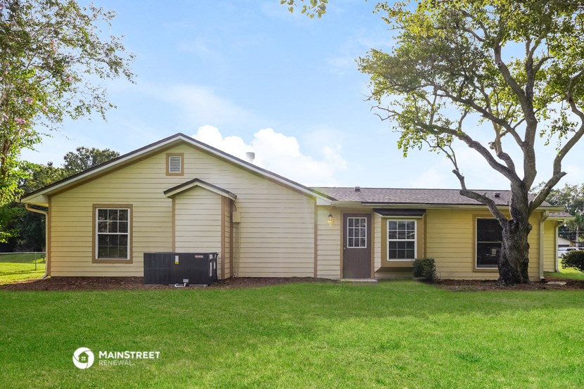 a yellow house with a big yard and a tree