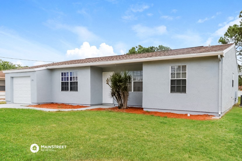 a white house with a lawn and a palm tree