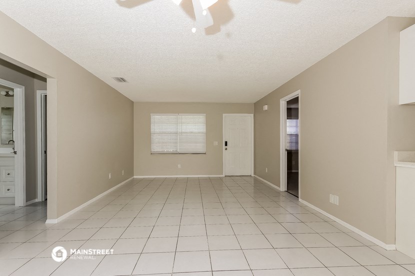 a spacious living room with tile flooring and a door to the bathroom