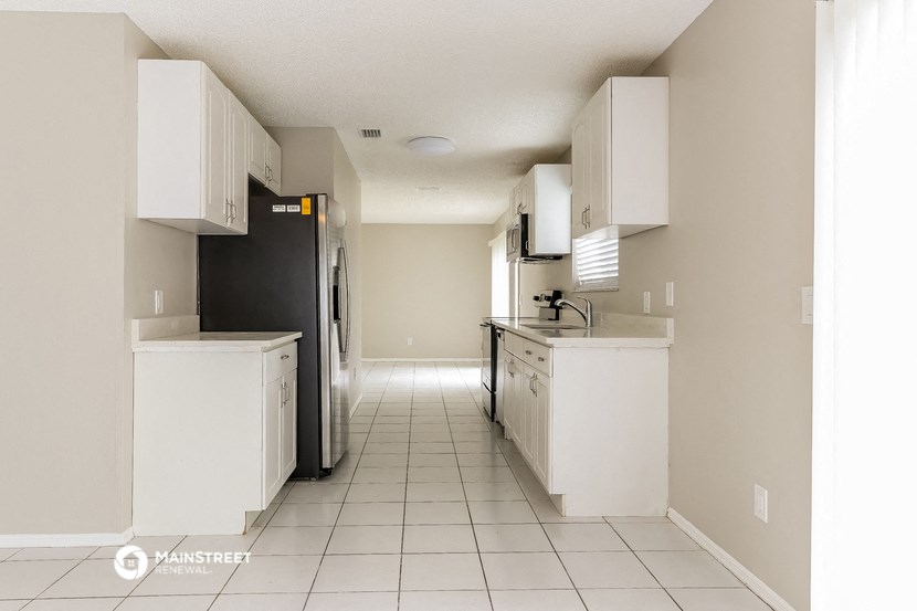 an empty kitchen with white cabinets and a black refrigerator