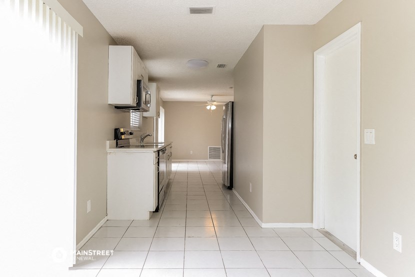 an empty kitchen and hallway with a white tiled floor