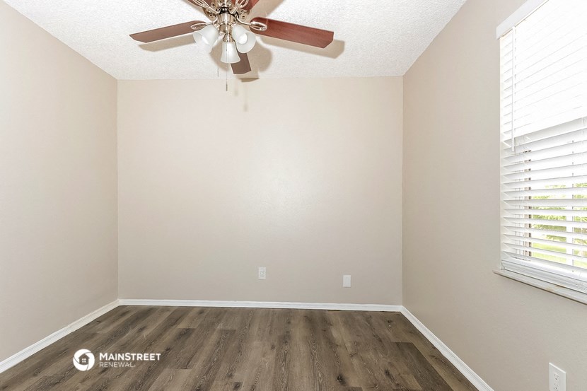 an empty room with a ceiling fan and wood floors