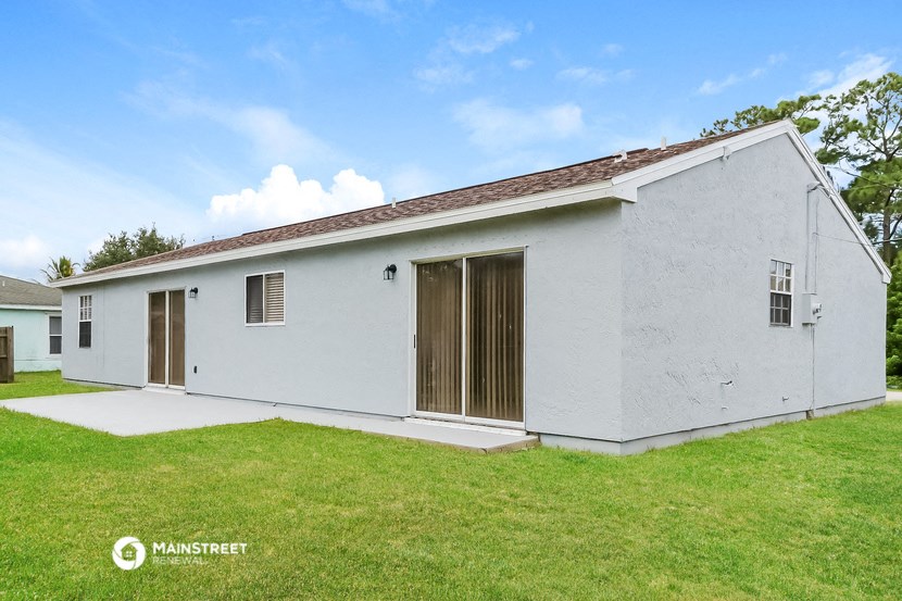 a small white house with a grass yard and a garage