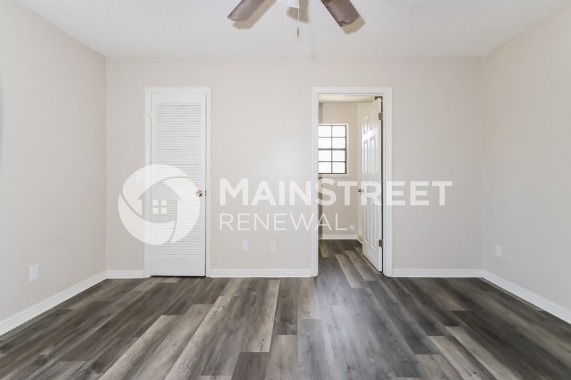 a renovated living room with hardwood floors and a door to a hallway