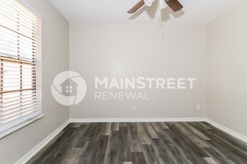 a living room with wood floors and a ceiling fan