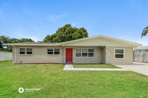 a white house with a red door and a grassy yard