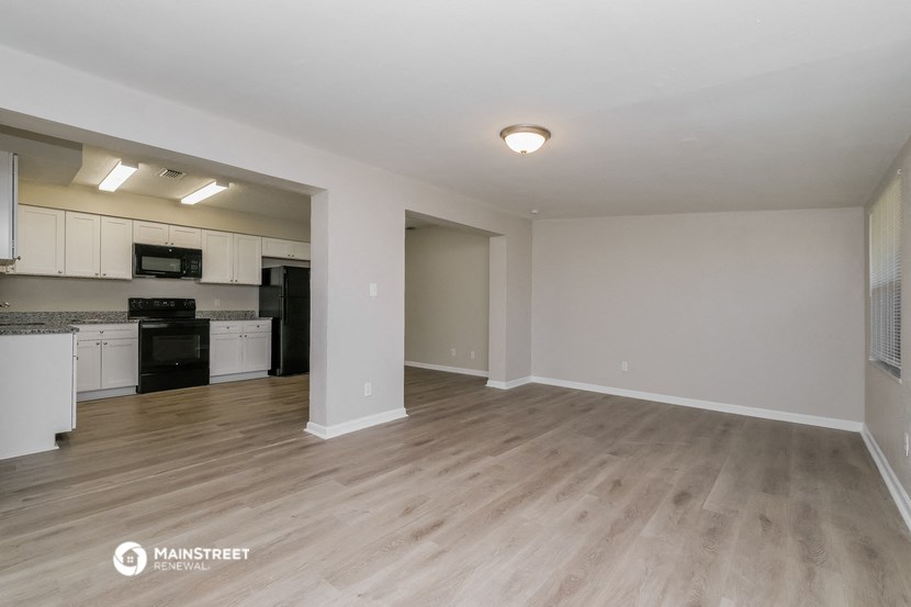 the spacious living room and kitchen of an apartment