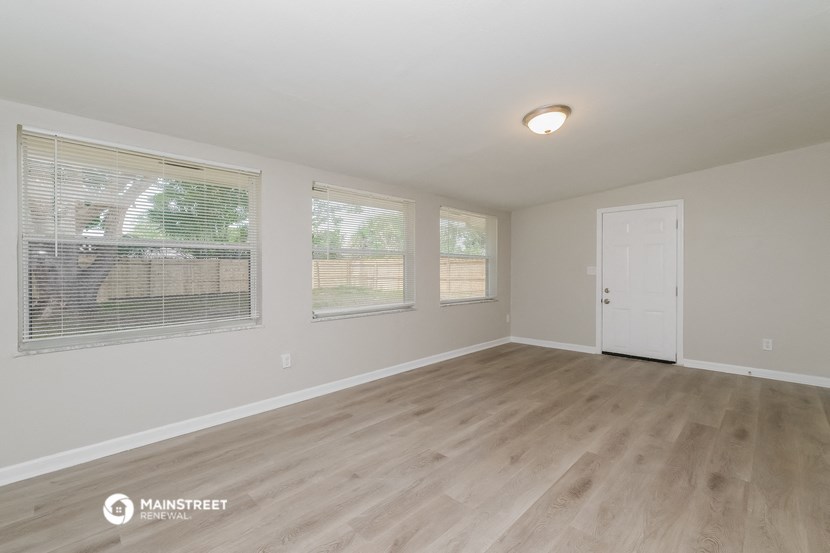 the spacious living room with wood flooring and a white door
