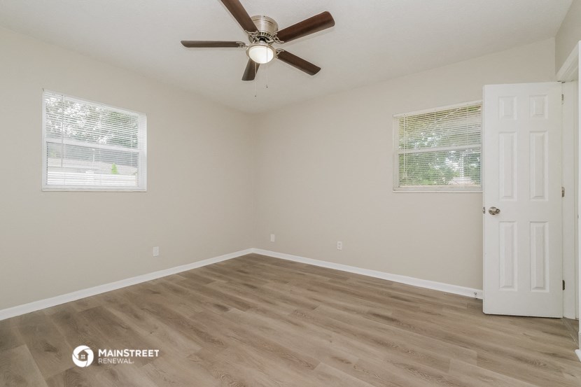 the spacious living room with hardwood floors and a ceiling fan