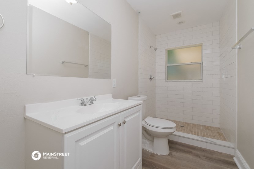 a white bathroom with a toilet and a sink and a mirror