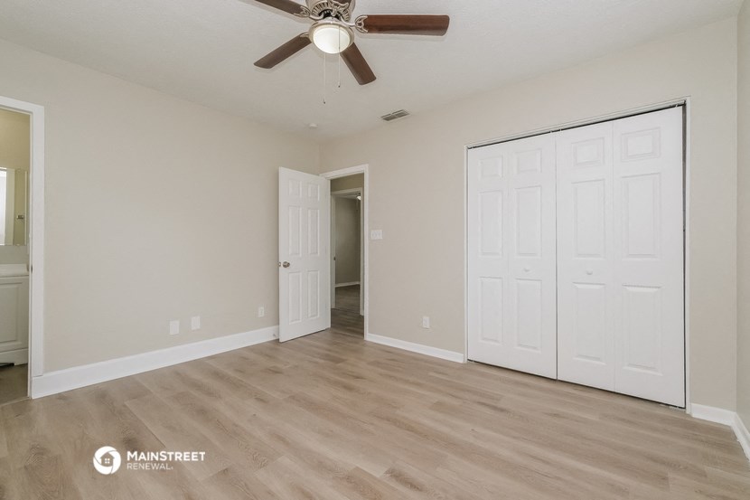 an empty living room with a ceiling fan and a closet