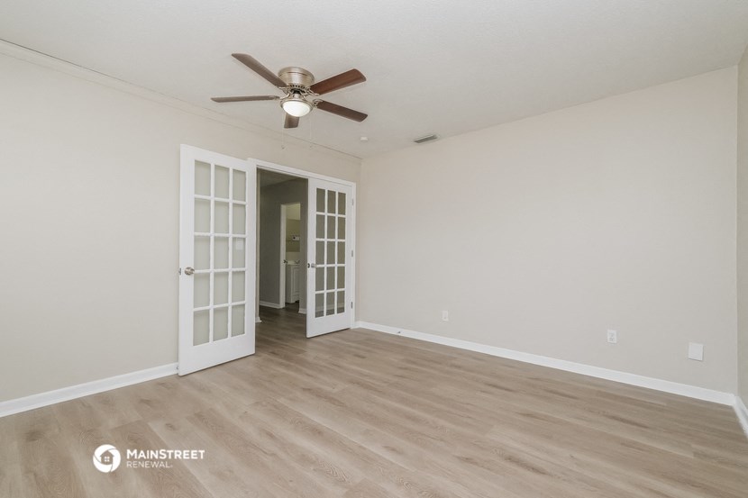 the living room of an empty house with a ceiling fan