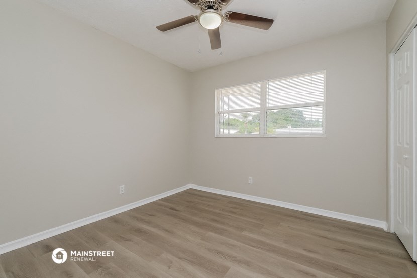 an empty room with a ceiling fan and a window