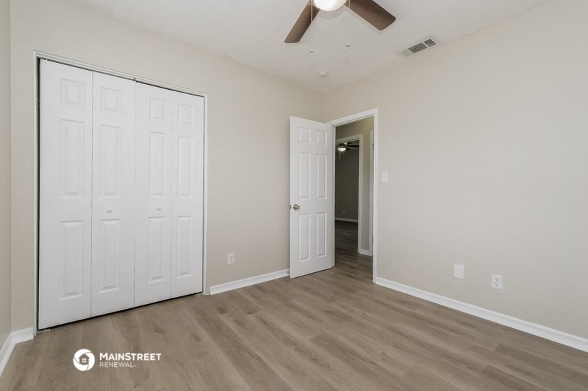 the spacious living room with two closets and a ceiling fan