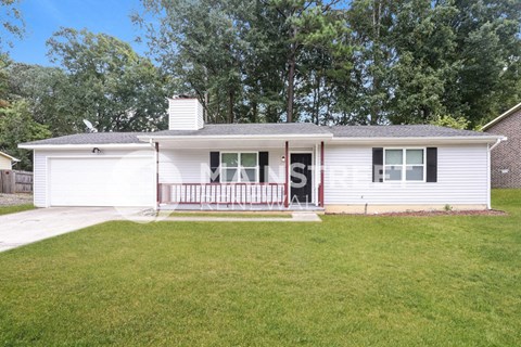 a small white house with a porch and a lawn