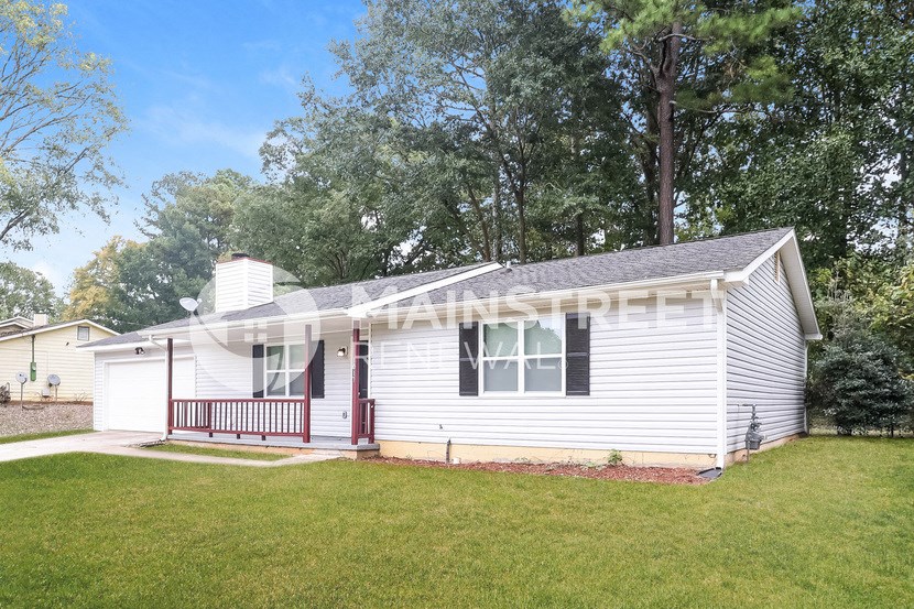 a small white house with a red porch and a lawn