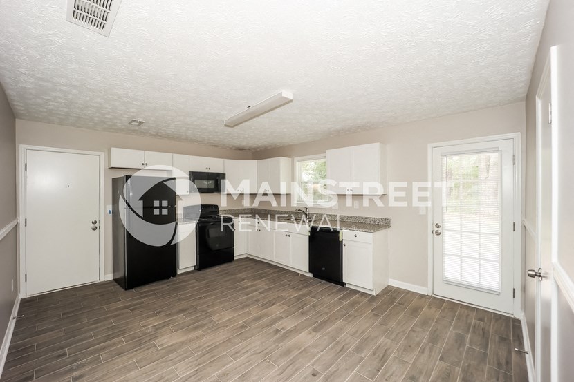 a renovated kitchen with white cabinets and a wood floor