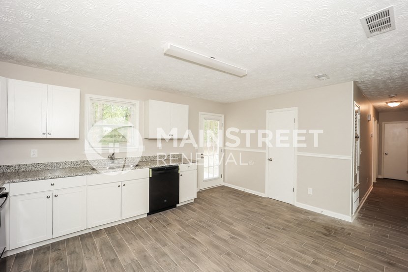 a kitchen with white cabinets and a counter top and a refrigerator