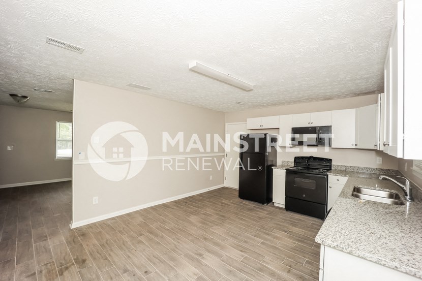 a studio apartment with a kitchen and a hard wood floor