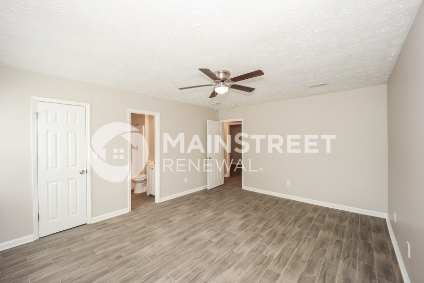 a living room with a ceiling fan and a door to a bedroom