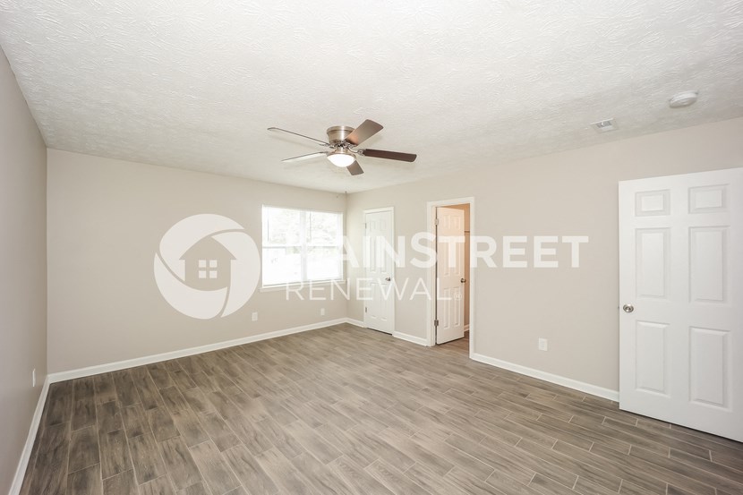 an empty living room with a ceiling fan and a door