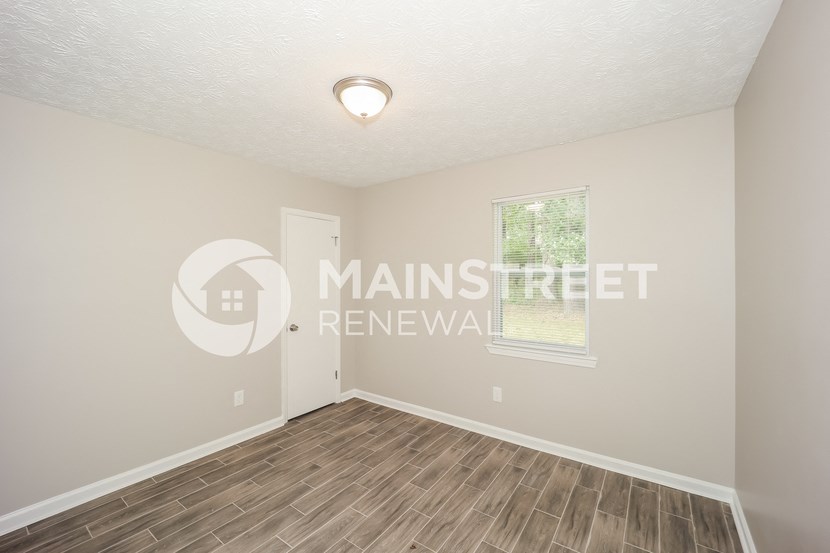 a bedroom with a hard wood floor and a window