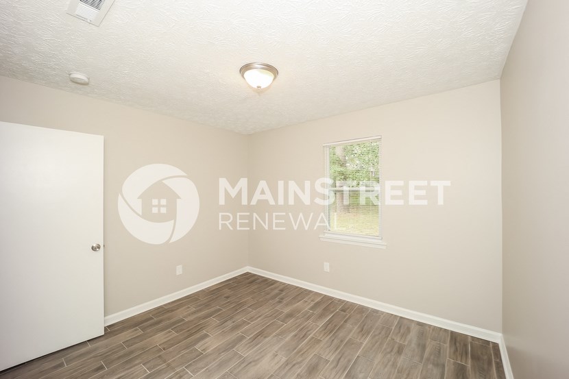 a bedroom with a hard wood floor and a window