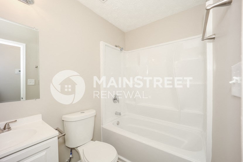 a white bathroom with a tub and a sink and a toilet