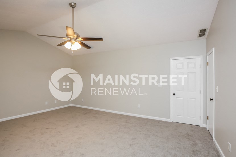 a bedroom with a white wall and a ceiling fan
