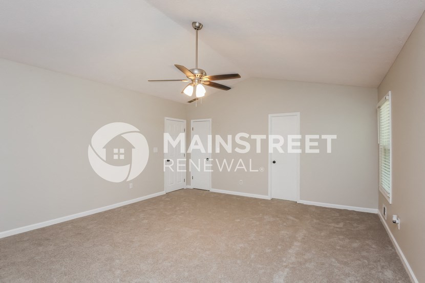 a bedroom with a carpeted floor and a ceiling fan